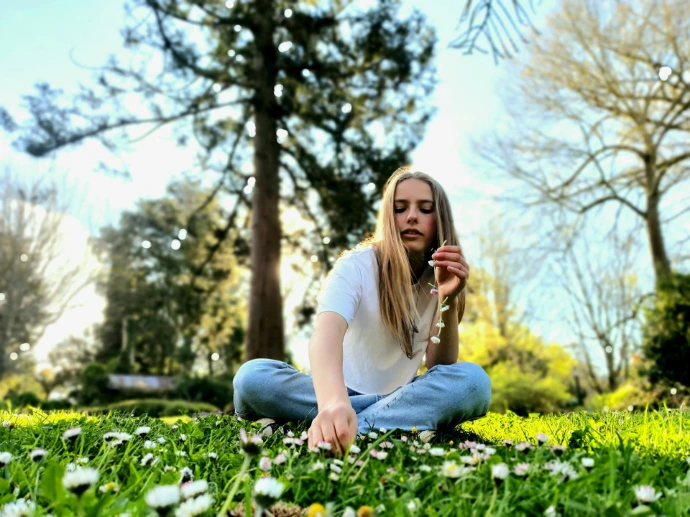 a woman sitting in the grass with a cell phone